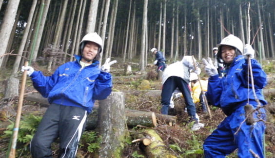 地元中学生が森の中で植林の作業をしている写真